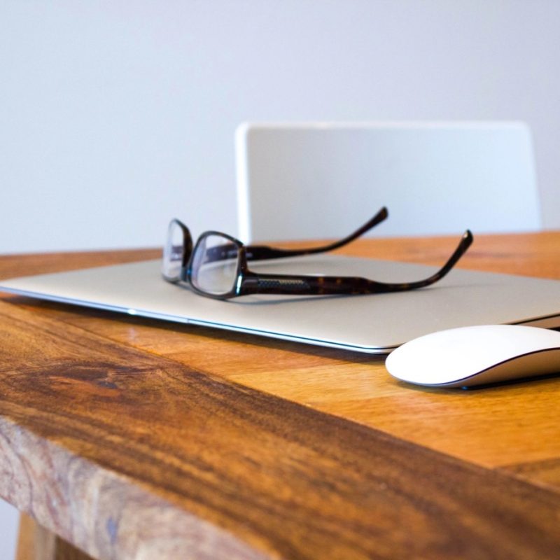 wood desk with laptop and glasses
